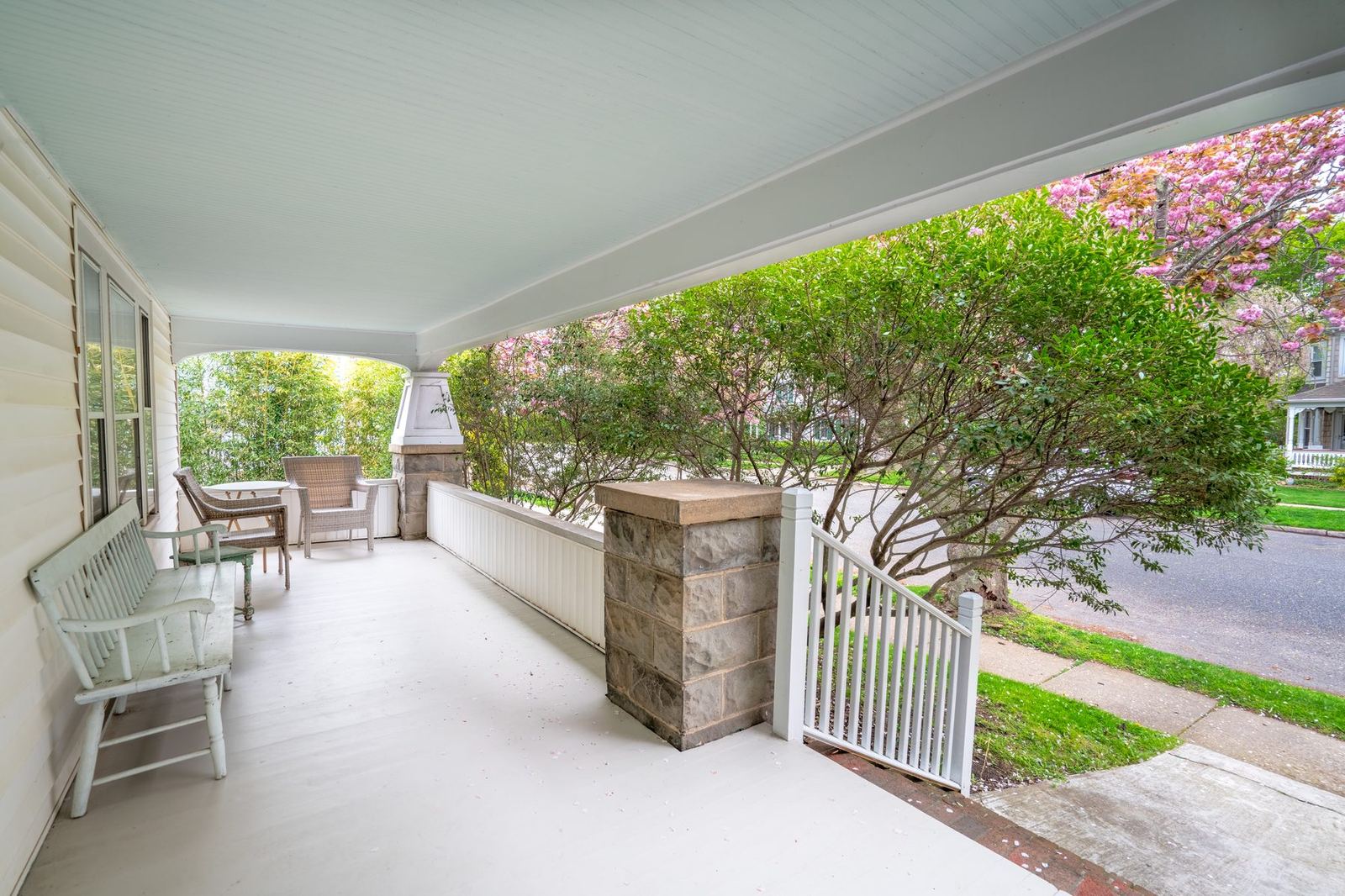 Wraparound front porch with corner fireplace and white wicker chairs